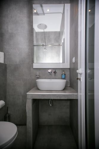 a bathroom with a sink and a mirror and a toilet at Sophia seaview suites & restaurant in Nea Vrasna
