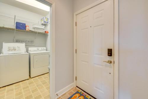 a laundry room with a white door and a washer and dryer at Pool Access and 11 Mi to Beach Calabash Condo! in Calabash