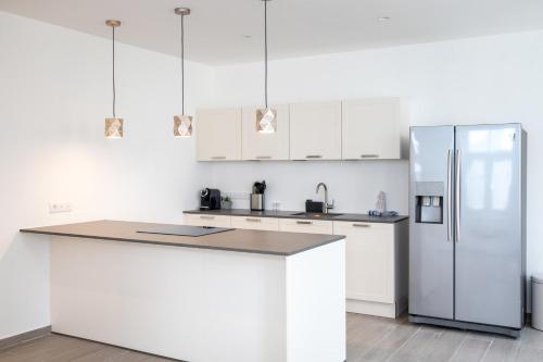 a kitchen with white cabinets and a refrigerator at Willemstad Historic City Suites in Willemstad