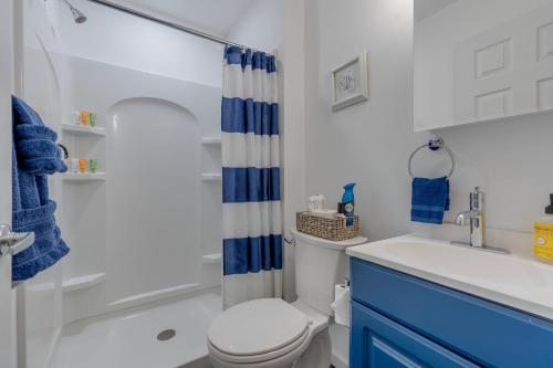 a bathroom with a white toilet and a blue shower curtain at Cozy 2BR Getaway Just 3 5 Blocks to Beach & Boards in Belmar