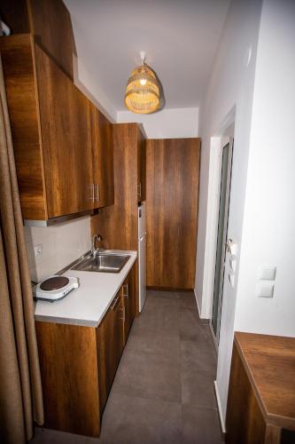 a kitchen with wooden cabinets and a sink at Sophia seaview suites & restaurant in Nea Vrasna