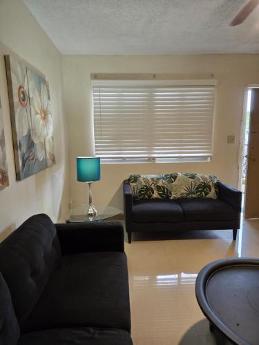 a living room with a black couch and a table at 2Bed1Bath - Central Island Haven in Sinajana