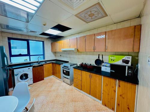 a kitchen with wooden cabinets and a washer and dryer at Lux Living Room in Ajman 