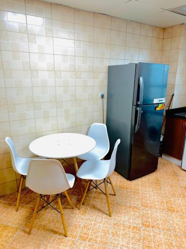 a table and chairs and a refrigerator in a kitchen at Lux Living Room in Ajman