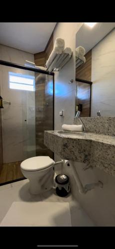 a bathroom with a toilet and a granite counter top at Hotel Minorus in Aparecida