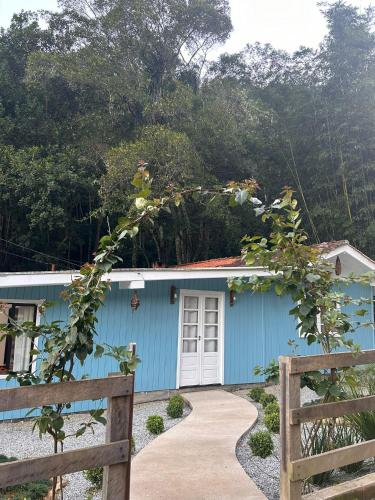 a blue house with a fence in front of it at Morada encanto da cachoeira in Aguas Mornas
