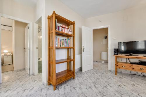 a living room with a tv and a book shelf at Villa FORTUNA - Apartamentos у Estudios para vacaciones con territorio y piscina común, Calpe in Calpe