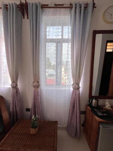 a room with a window with curtains and a table at Nungwi Beach Front in Nungwi
