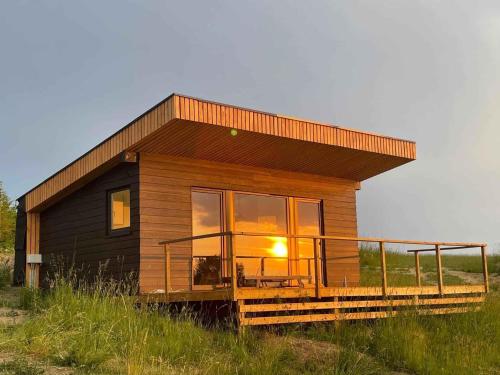 a small house with a large window on a field at Cozy Tiny House In Nature - Holiday Home D in Sejerby