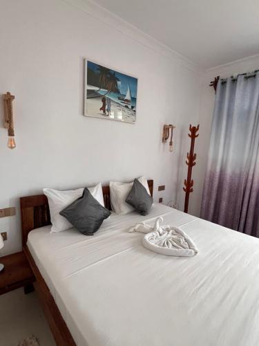 - une chambre dotée d'un lit avec des draps blancs dans l'établissement Nungwi Beach Front Ex Sunrise Beach Nungwi, à Nungwi
