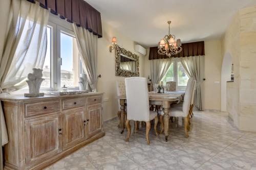 a dining room with a table and a chandelier at Villa FORTUNA - Apartamentos у Estudios para vacaciones con territorio y piscina común, Calpe in Calpe