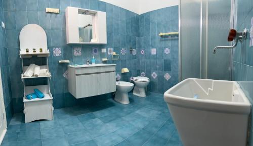a blue tiled bathroom with a sink and a toilet at Sweet home Angi in Marsala