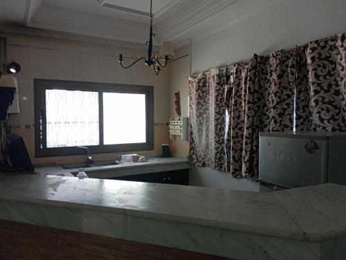una cocina con fregadero y una ventana con cortinas en Le petit VIP, en Aïn El Turk