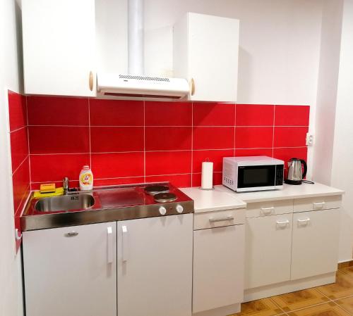 a kitchen with a sink and a red wall at TRI KRALJA - THREE KINGS Apartments in the center with private parking in Imotski