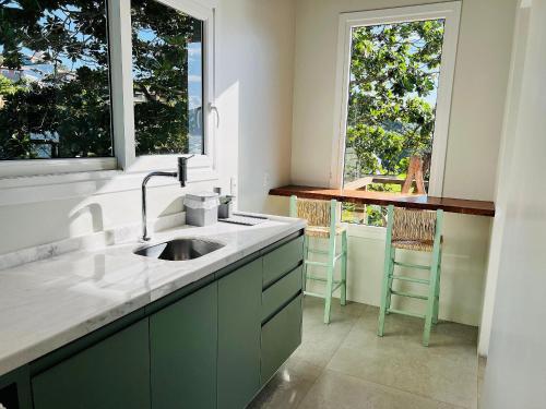 a kitchen with a sink and two windows at Spa Jacuzzi, Lareira, Beira mar, 4 Suítes in Garopaba