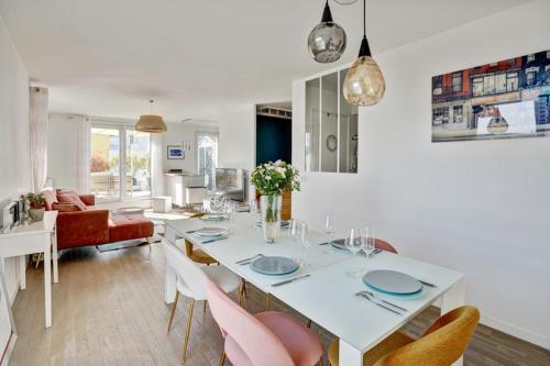 une salle à manger blanche avec une table et des chaises blanches dans l'établissement Duplex 3 chambres grande terrasse dernier étage, à Nanterre