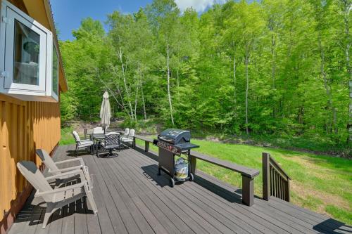 a wooden deck with a grill and chairs on it at Catskills Cabin Rental with Hot Tub and Amazing Views! in Stamford