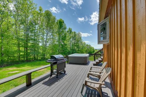 a deck with a grill and chairs on a house at Catskills Cabin Rental with Hot Tub and Amazing Views! in Stamford