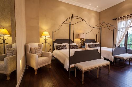 a bedroom with a four poster bed and chairs at Bastión Luxury Hotel in Cartagena de Indias