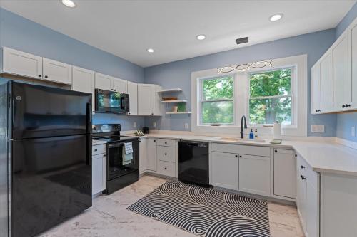 a kitchen with white cabinets and black appliances at 5bd Movie Theater - 7mins to UND - Backyard BBQ in South Bend
