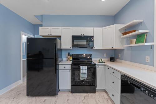 a kitchen with a black refrigerator and white cabinets at 5bd Movie Theater - 7mins to UND - Backyard BBQ in South Bend