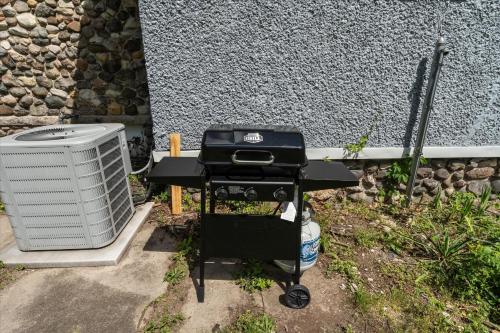 a grill and a air conditioner next to a wall at 5bd Movie Theater - 7mins to UND - Backyard BBQ in South Bend