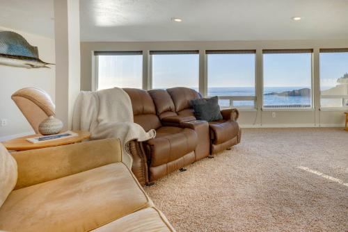 a living room with a brown leather couch and windows at Ocean Front Condo! Spectacular Ocean Views! Walk to Everything! in Depoe Bay