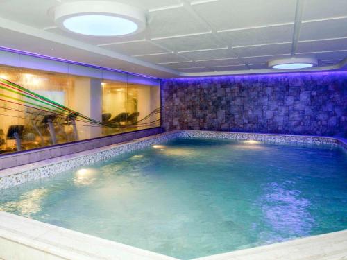 einen großen Pool in einem Zimmer mit lilafarbener Beleuchtung in der Unterkunft Novotel Dammam Business Park in Dammam