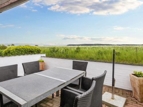 een tafel en stoelen op een patio met uitzicht op een veld bij 6 person holiday home in Thisted in Arup