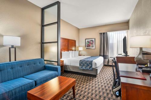 a hotel room with a bed and a blue couch at Best Western Plus Greenville I-385 Inn & Suites in Greenville