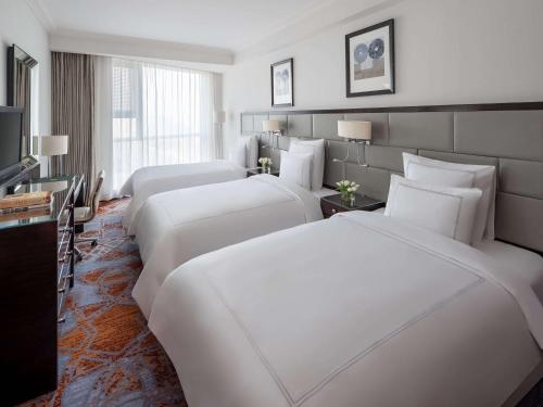 um quarto de hotel com três camas e uma televisão em Swissotel Makkah em Meca