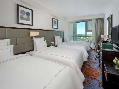 um quarto de hotel com quatro camas e uma televisão em Swissotel Makkah em Meca