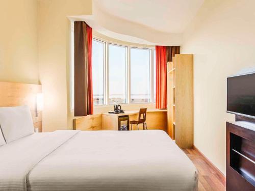 a hotel room with a bed and a television at Ibis Yanbu in Yanbu