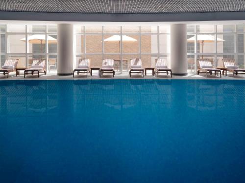 een groot zwembad in een gebouw met stoelen bij Mövenpick Hotel Qassim in Buraydah