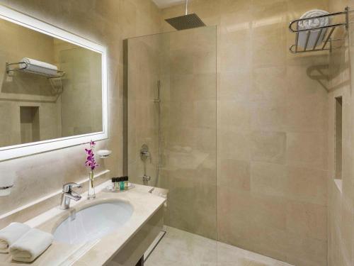 ein Bad mit einem Waschbecken und einer Dusche in der Unterkunft Mövenpick Hotel Qassim in Buraida