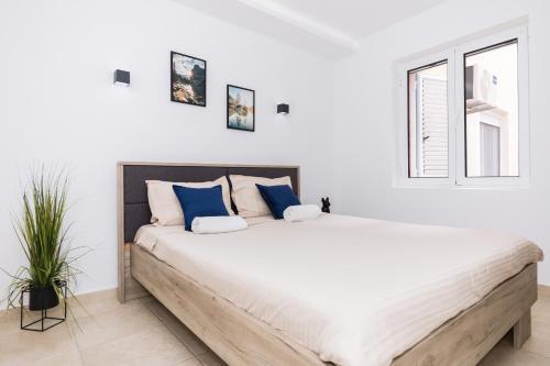 ティヴァトにあるPaunovic Apartmentsの白いベッドルーム(青い枕の大型ベッド付)