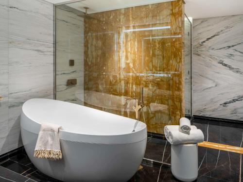 利雅德的住宿－Movenpick Hotel and Residences Riyadh，浴室配有白色浴缸和淋浴。