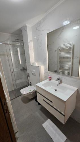 a white bathroom with a sink and a shower at Apartment Lana in Sarajevo