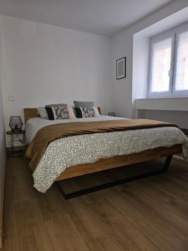 une chambre avec un grand lit dans une pièce blanche dans l'établissement Centre bourg Ouistreham, à Ouistreham