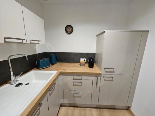 une cuisine avec des armoires blanches et un évier dans l'établissement Centre bourg Ouistreham, à Ouistreham