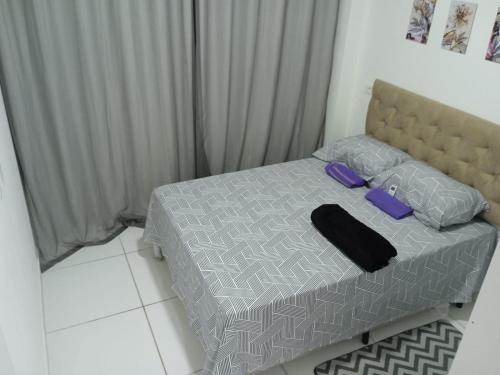 a small bedroom with a bed with purple pillows at Vizinho ao Shopping Caruaru Cobertura 14 andar in Caruaru