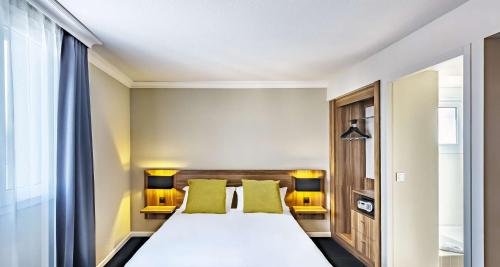a bedroom with a large white bed with green pillows at Best Western Hotel Atrium Valence in Valence