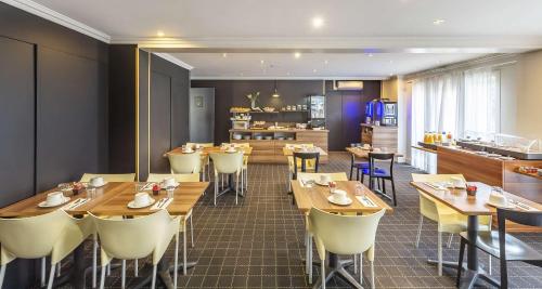 a restaurant with wooden tables and chairs and a kitchen at Best Western Hotel Atrium Valence in Valence