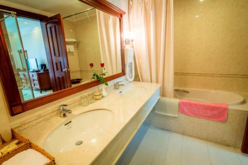 a bathroom with a sink and a mirror and a tub at Saigon Kimlien Resort Cualo in Cửa Lô