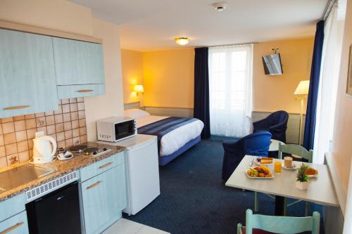 a hotel room with a king sized bed and a kitchen at Hotel Montbrillant in Geneva