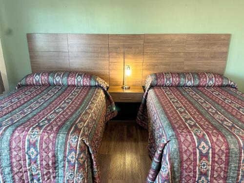 a hotel room with two beds and a night stand at Captain John's Motel in Charleston