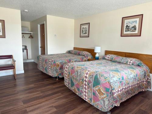 a hotel room with two beds and a chair at Captain John's Motel in Charleston
