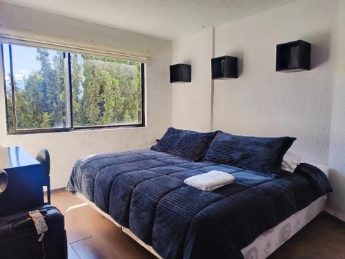 a bedroom with a blue bed with a large window at Hotel Bellavista Quito in Quito