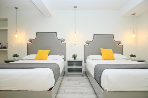 two beds with yellow pillows in a room at Rio Suites in Tijuana