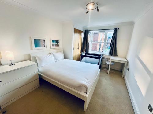 a small bedroom with a white bed and a desk at Exquisite City Centre Apartment - 2 Bed 2 Bath - Free Parking - Netflix Amazon Disney Enabled Smart TV in Birmingham